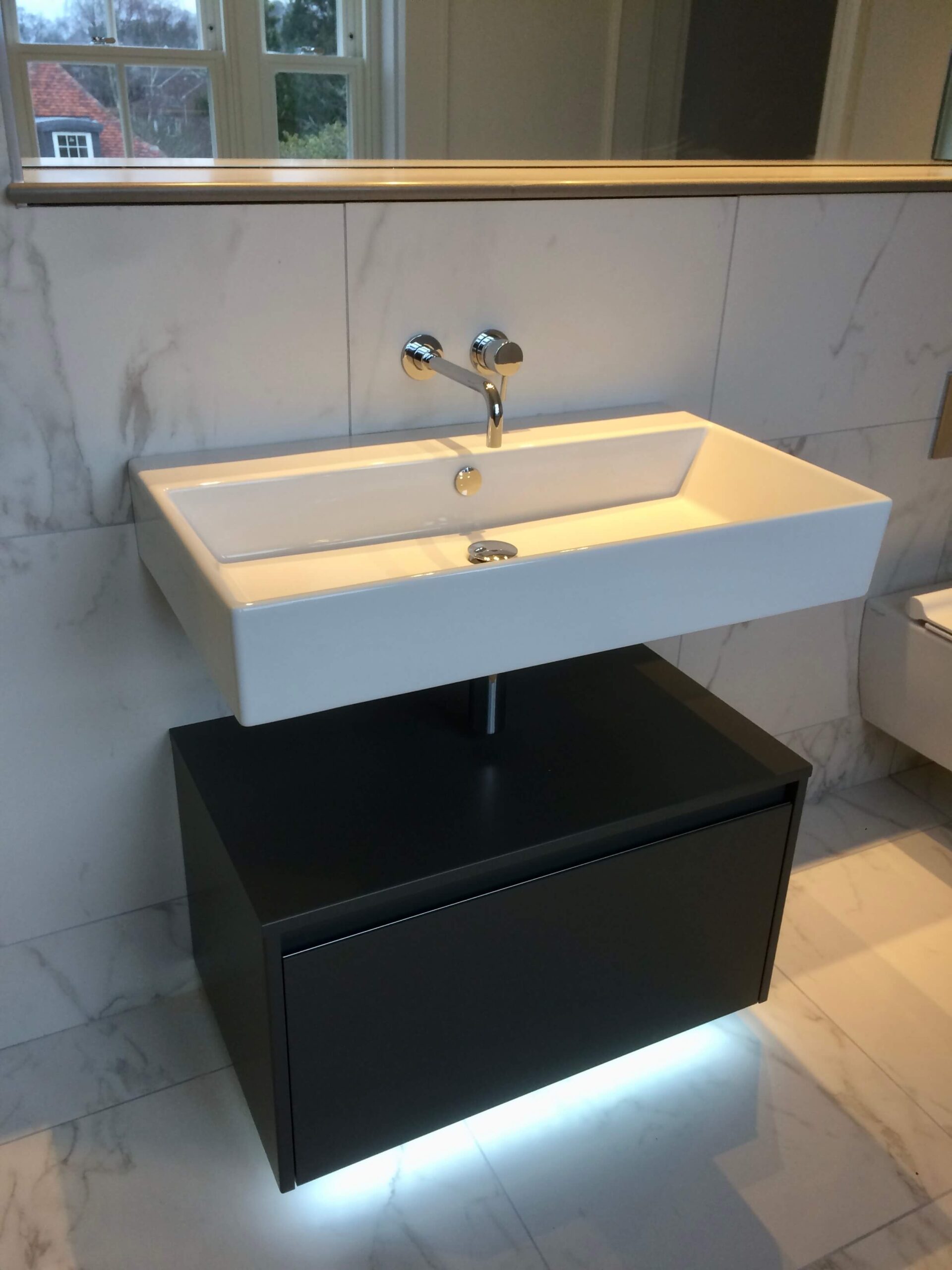 A modern bathroom with black cabinet under sink.