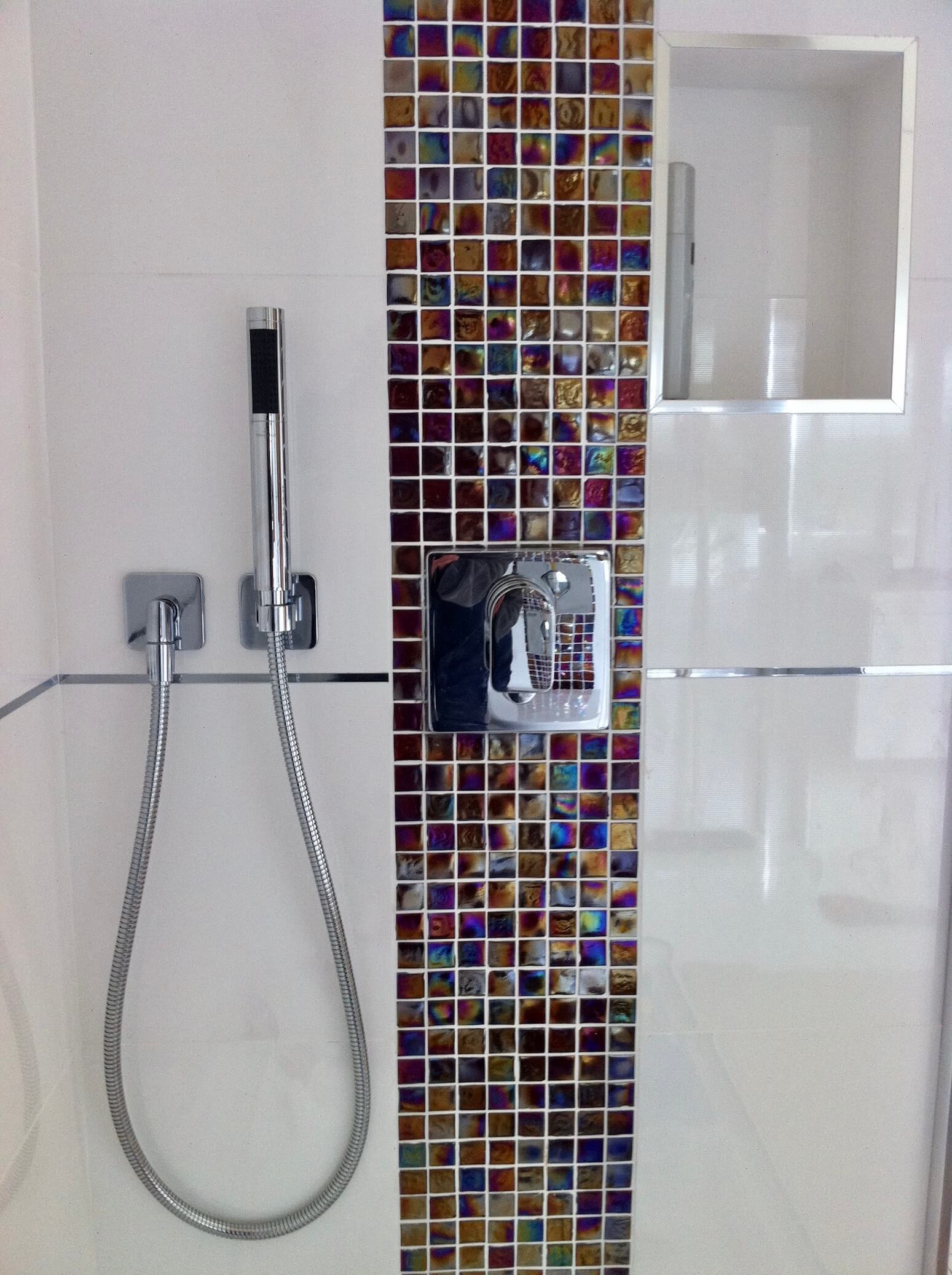Beautifully tiled shower room with a strip of mosaic tiles as a main feature in the shower.