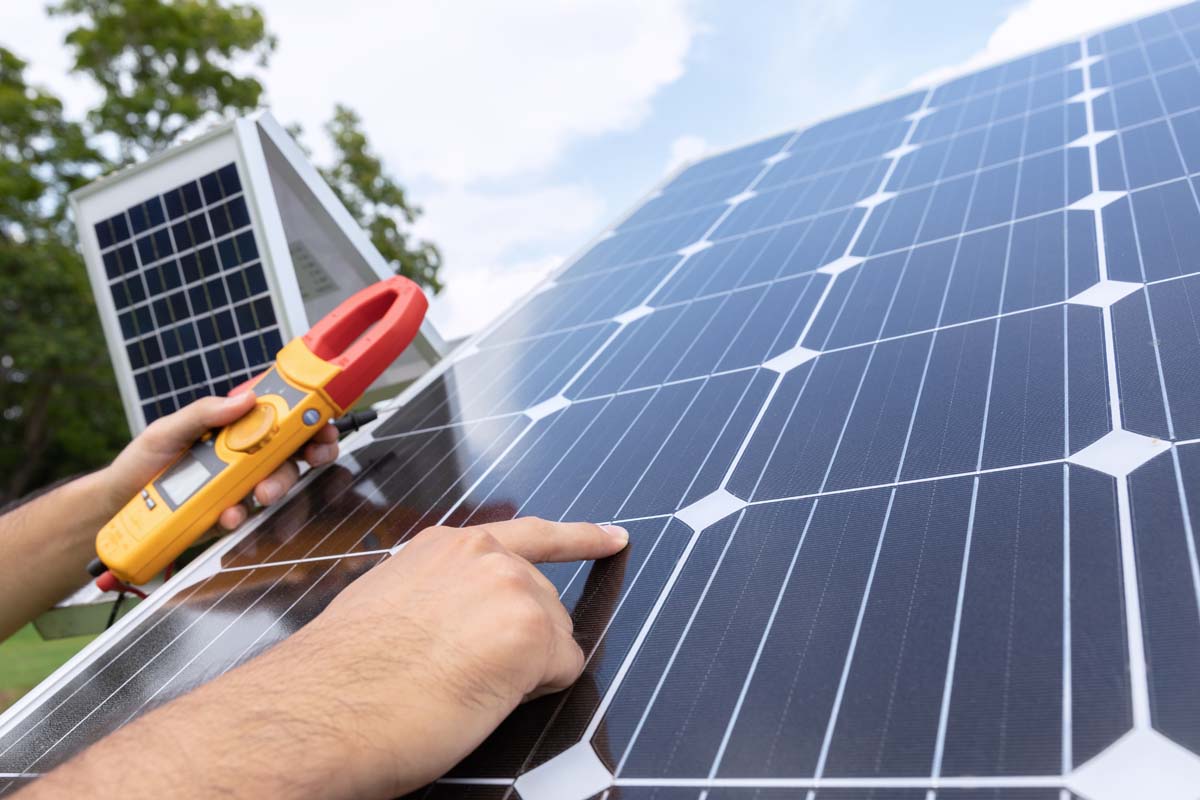 Engineer solar photovoltaic panels station checks with measurement tool.